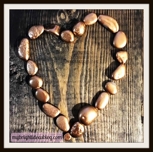 How to make pebble art with small, rose gold painted stones on a wood plaque. Shape into a heart to say I love you! mybrightideasblog.com